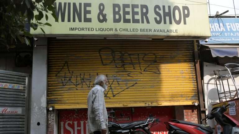 An old man passing through a closed liquor shop